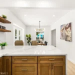 Kitchen with wood cabinets, marble counter, open shelves, and dining area in back