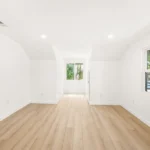Empty room with white walls, wood floor, and windows