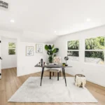 Room with desk, chair, plant, wall art, and big windows