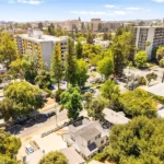 Aerial view of city buildings, green trees, and cars on streets