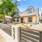 Two story California real estate house with gray roof, white walls, front yard, fence, driveway, and garage