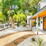 California real estate home front yard with path, plants, gravel, trees, and house