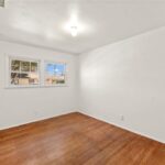 Empty room with white walls, wood floor, window, and ceiling light