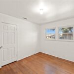 Empty room with white walls, wood floor, window, and closet doors