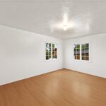 Empty room with white walls, wood floor, and big windows