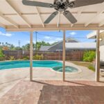 California real estate home patio with ceiling fan, pool, and green plants