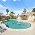 backyard with pool, palm trees, and small patio