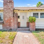 California real estate house with white walls, brick chimney, path, and grass