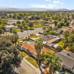 Aerial view of California homes, palm trees, road, and mountains