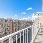 California apartment buildings with balconies by water and balcony with umbrella and chairs