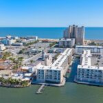 Aerial view of coastal city with tall beach buildings, canals, homes, and ocean