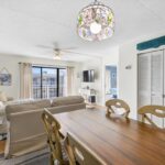 Living dining area with wood table, beige sofas, glass doors to balcony, and lamp