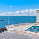 Pool by water with building in back and blue sky