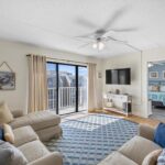 Living room with beige sofa, wall TV, and glass doors to balcony