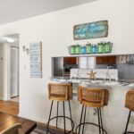 Kitchen with wicker bar stools, marble counter, starfish decor, and beach wall art