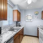 Kitchen with wood cabinets, marble counter, blue walls, sink, stove, and microwave